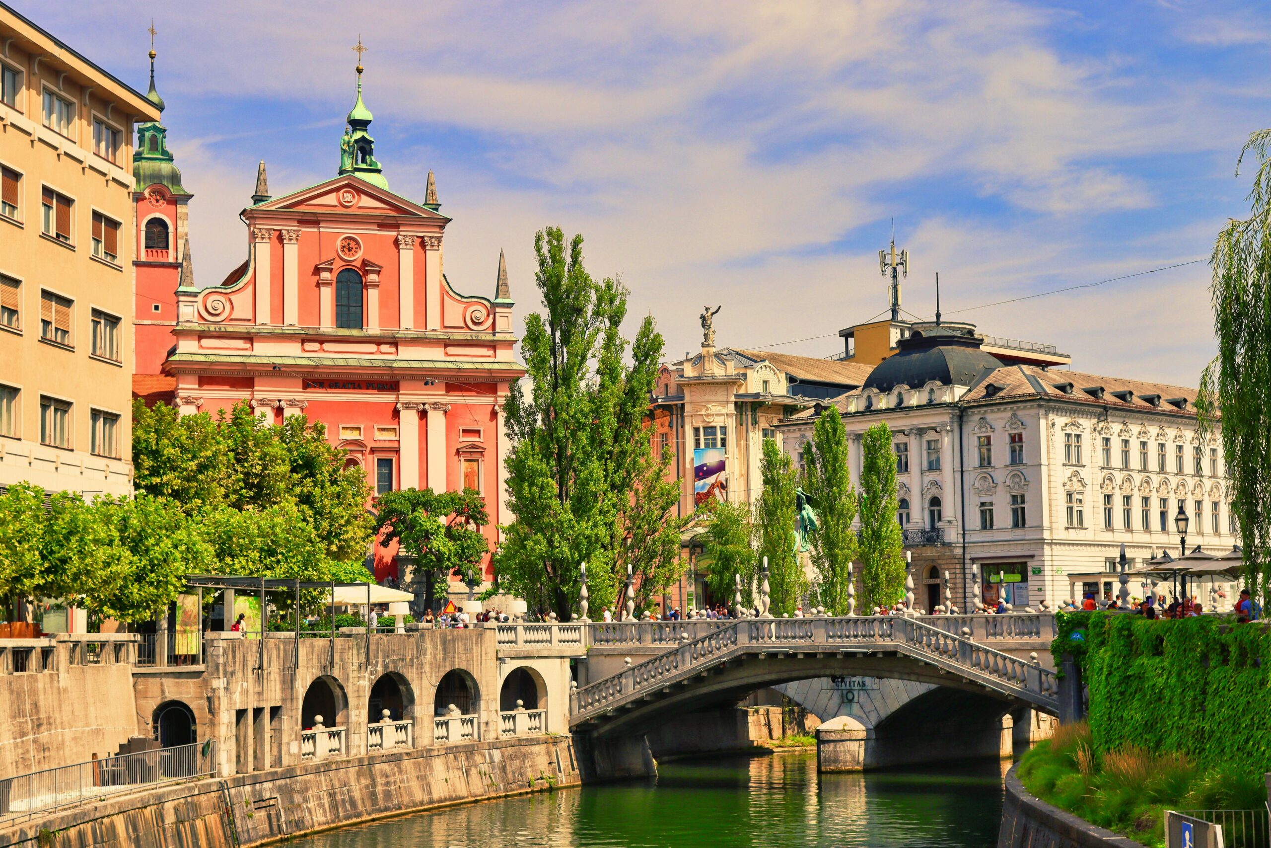 Explore Ljubljana's vibrant cityscape with the Triple Bridge and Franciscan Church on a sunny day.
