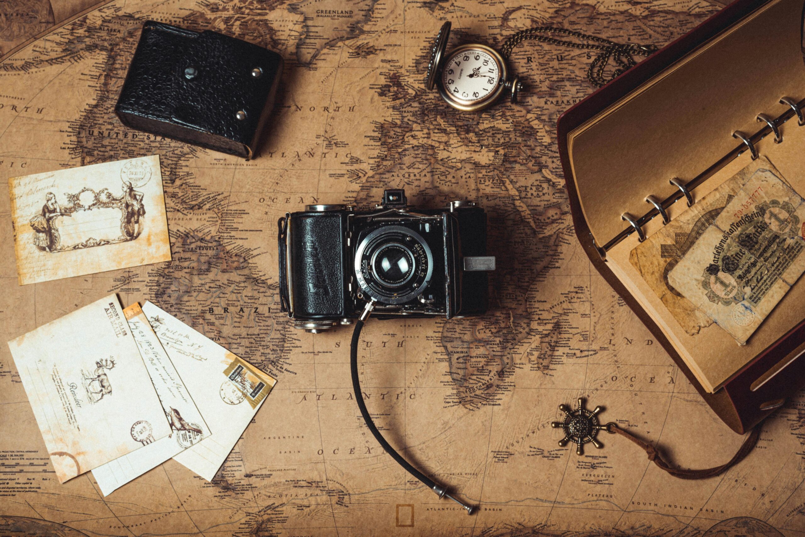 A nostalgic flat lay combining vintage travel items, an analog camera, and a world map.