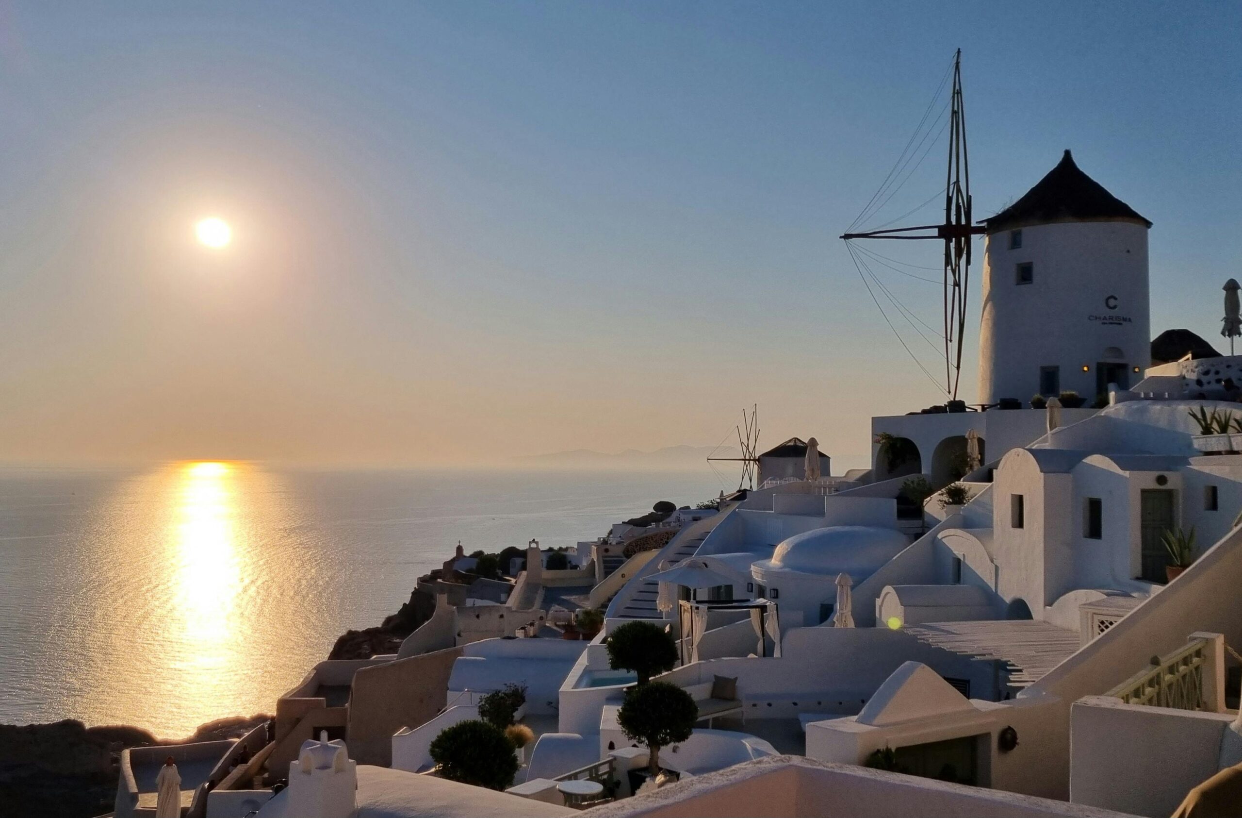Breathtaking sunset over Santorini's iconic white structures and windmill, capturing serene beauty.